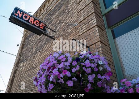 A neon Norge sign hanging on a brick wall with a flower basket in Pomeroy, Washington, USA Stock Photo