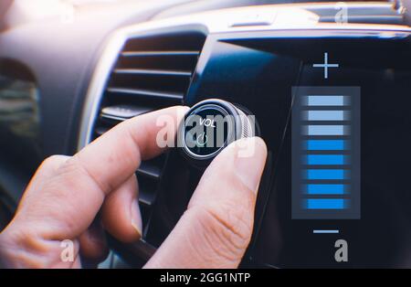 Car owner hand turning volume button of a car audio system in the car Stock Photo