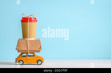 Retro toy car delivering food order on blue background. Copy space Stock Photo
