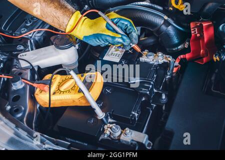 Technician checking DC voltage stable of the car battery with digital multimeter probe Stock Photo