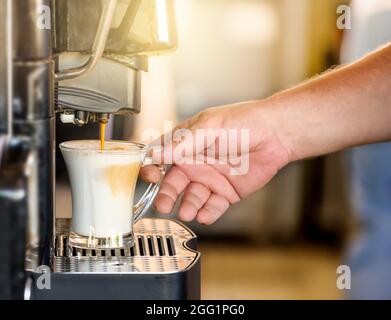 Hand taking coffee cup in automated coffee making machine. Stock Photo