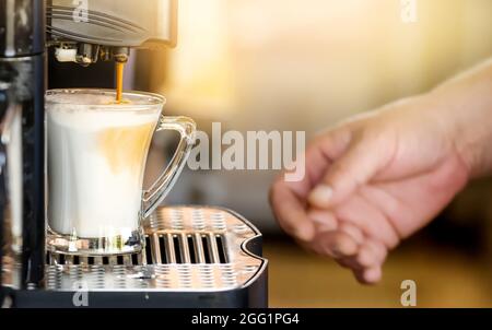 Hand taking coffee cup in automated coffee machine. Stock Photo