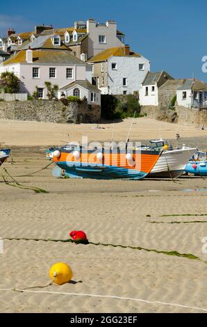 St. Ives Harbour Beach Cornwall - A Boat Rests On The Beautiful Sands With Picturesque White Houses Behind Stock Photo