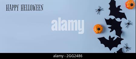Holiday Halloween banner. Paper decor bats, spiders and pumpkins lie on a blue background. Inscription Happy Halloween, copying space, flat layout Stock Photo