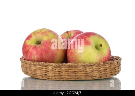 Three juicy organic apples in a bowl made of straw, close-up, isolated on white. Stock Photo