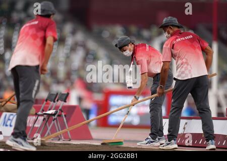 Tokio, Japan. 28th Aug, 2021. Paralympics: Athletics, long jump, in the Olympic stadium. Volunteers smoothing the sand before the competition. Credit: Marcus Brandt/dpa/Alamy Live News Stock Photo