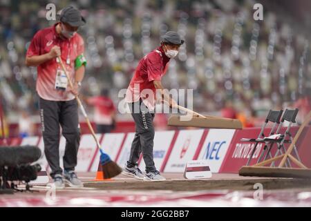 Tokio, Japan. 28th Aug, 2021. Paralympics: Athletics, long jump, in the Olympic stadium. Volunteers smoothing the sand before the competition. Credit: Marcus Brandt/dpa/Alamy Live News Stock Photo