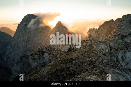 Man on the top of the hill watching wonderful scenery in mountains during summer colorful sunset.  Beautiful moment the miracle of nature Stock Photo