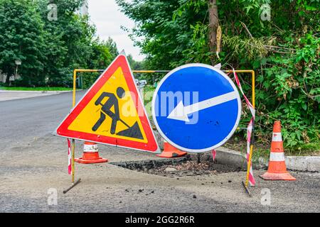 Road signs indicating the repair of asphalt and the direction to bypass the dangerous section Stock Photo