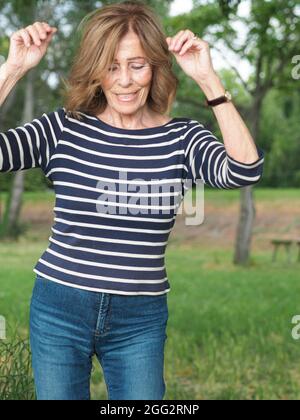 Elder Italian woman in striped clothes enjoying the vibes in a park Stock Photo