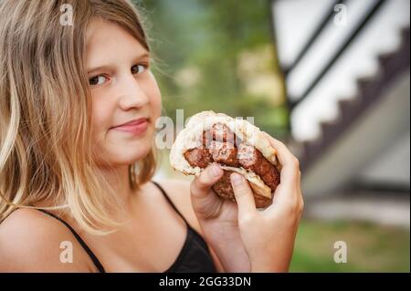 BBQ grilling party. Beautiful girl enjoying barbecue at outdoors. Food, people and family time concept Stock Photo