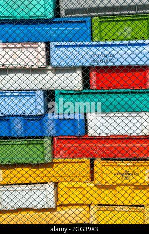 Hel, Poland - 08.02.2021: Lot of colorful plastic boxes, usually used to store fish, mounted in big blocks behind a steel fence in port of Hel Stock Photo