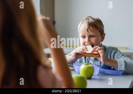 schoolboy eating sandwich near girl on blurred foreground Stock Photo