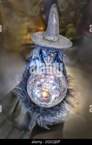 Wicked witch Halloween decoration with crystal ball and sparkly hat against bokeh background Stock Photo