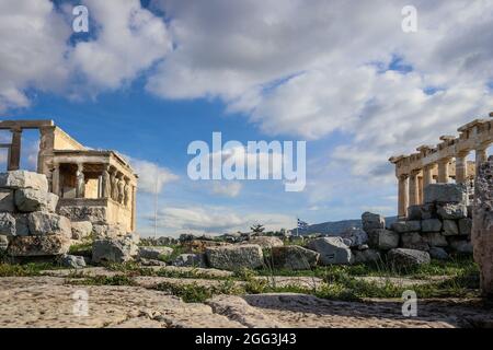 Athens Accropolis with edges of Parthenon and Caryatid porch of the Erechtheion with Greek flag flying between and beautiful blue cloudy sky - low lev Stock Photo