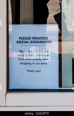 Social Distancing sign in shot window printed on white paper with a few bugs and some grunge - realistic. Stock Photo