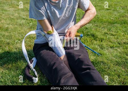 Young man with disability puts on prosthesis in yard Stock Photo