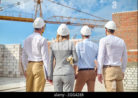 Four people examining in safety helmets a new construction object Stock Photo