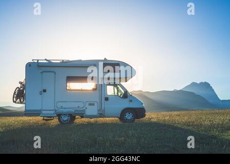 Sunset dramatic sky over camper van in Campo Imperatore highlands, Abruzzo, Italy. Epic clouds above unique highlands and rocky mountains landscape, a Stock Photo