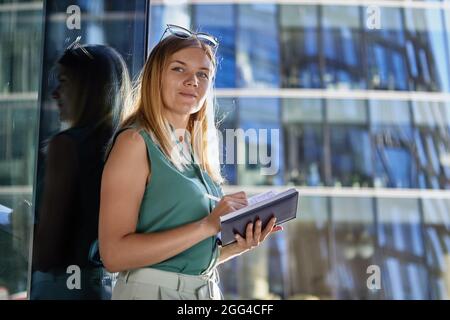 Businesswoman is writing in diary near business center. Stock Photo