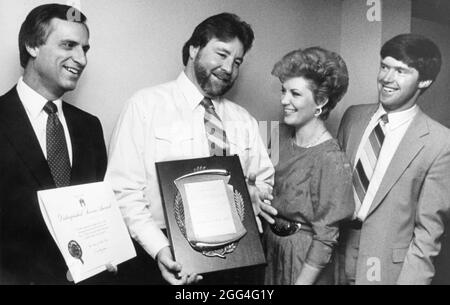 Austin Texas USA, circa 1984: Man holds award for heroism for pulling woman (standing next to him) from a burning car; at left is Mayor Ron Mullen and at right is a local church pastor. ©Bob Daemmrich Stock Photo