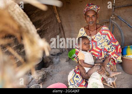 A Fulani African woman and her baby boy in front of their small hut in Ségou Region, Mali, West Africa. Stock Photo