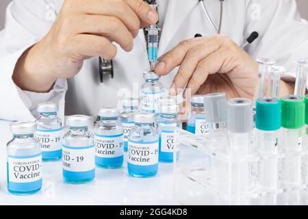 A doctor or a scientist in a laboratory coat holding a syringe with liquid vaccine vial.  Covid-19 vaccination concept. Stock Photo