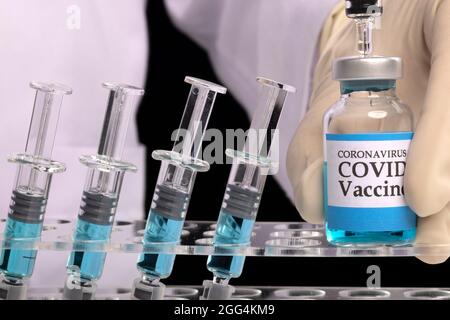 A doctor  holding a syringe with liquid vaccine vial. Vaccination, herd immunity concept. Stock Photo