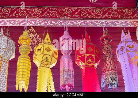 Traditional and elaborate design on northern Thai style paper lanterns hanging from the temple ceiling as religious offerings. Stock Photo