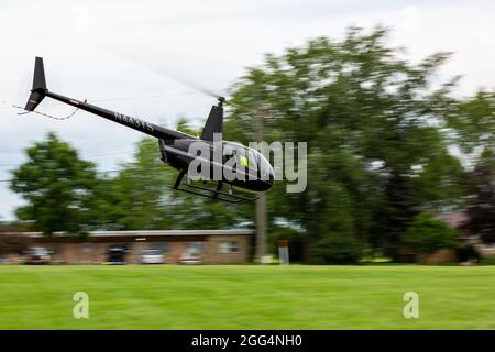 A Robinson R44 Raven II helicopter flies near the ground in Angola, Indiana, USA. Stock Photo