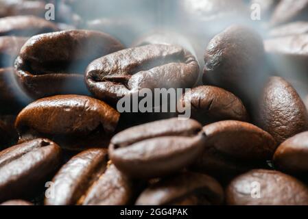 Heap of roasted coffee beans close-up view with smoke Stock Photo