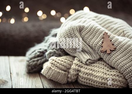 Cozy Christmas composition with a stack of knitted sweaters on a blurred background with bokeh. Stock Photo