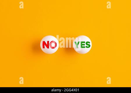 The words no and yes written on table tennis balls on yellow background. Stock Photo