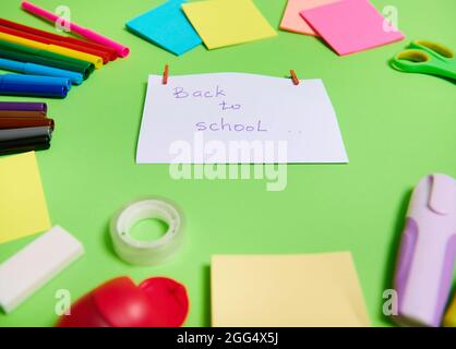 Soft focus on a white paper with lettering Back To School in the center of multi colored assortment of stationery office supplies and school accessori Stock Photo