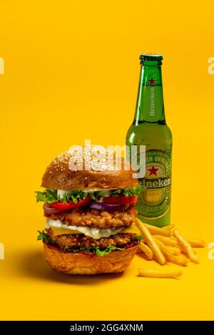 UKRAINE, KIEV - AUGUST 24, 2021: Big doubleburger with chicken cutlet, fries and Heineken beer Stock Photo