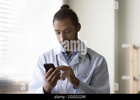 Concentrated young african american male doctor using cellphone. Stock Photo