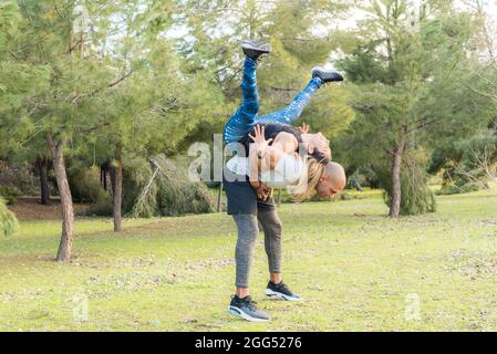 Fitness couple doing back to back lifting exercise in the park Stock Photo