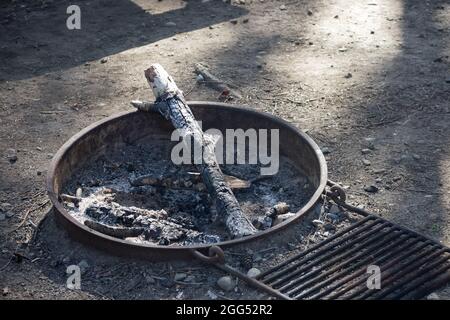 charcoaled piece of wood left blackened in a camp ground firepit Stock Photo