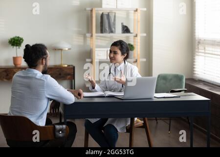 Confident young indian doctor consulting african patient. Stock Photo