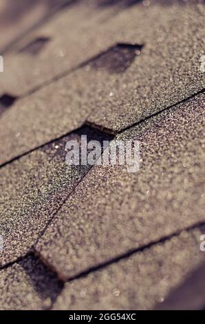 The roof is covered with asphalt shingles close-up.  Shingles - roofing material based on fiberglass, modified bitumen and stone sprinkles. Selective Stock Photo