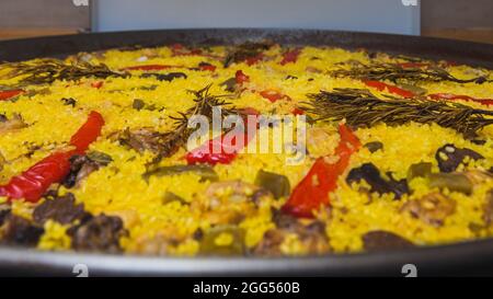 Close-up of a paella cooked at home with rice, red bell pepper, green beans, chicken and rabbit meat, mushrooms and some other ingredients, flavored w Stock Photo