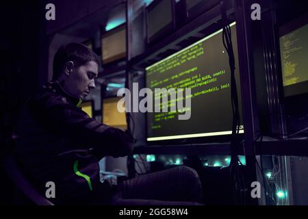 Hacker is working with computer typing text in dark room. Data security concept. Stock Photo