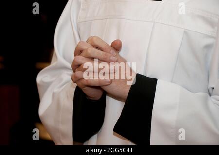 Young priest with his hands folded in prayer Stock Photo
