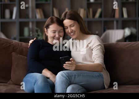 Happy young woman using cellphone with older mother. Stock Photo