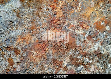 Rough stone surface with spots of rusty red and grey. Colorful texture in old copper mine Stock Photo