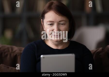 Happy older mature woman using digital tablet. Stock Photo