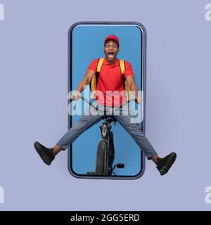 Black Courier On Bike In Smartphone Delivering Meal, Blue Background Stock Photo