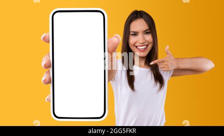 Woman showing white empty smartphone screen and pointing Stock Photo