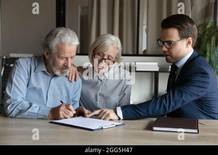 Mature couple signing contract, making deal with manager in office Stock Photo
