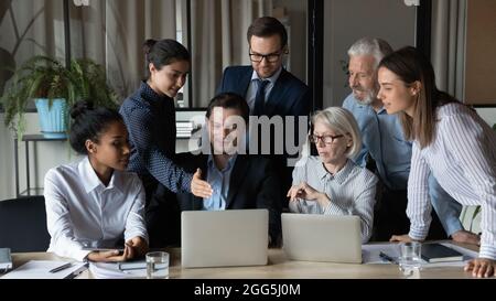 Diverse employees team working on online project, using laptops together Stock Photo